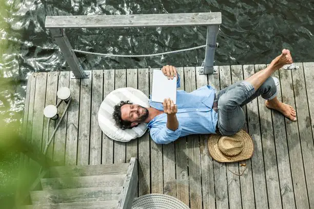 homme, lecture, détente, ponton, eau, extérieur, livre, sourire, été, coussin, chapeau, pieds nus, bois, chemise, bleu, calme, loisir, ensoleillé