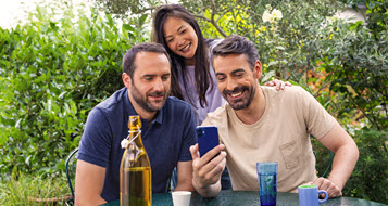 Un homme montre son smartphone à ses deux amis