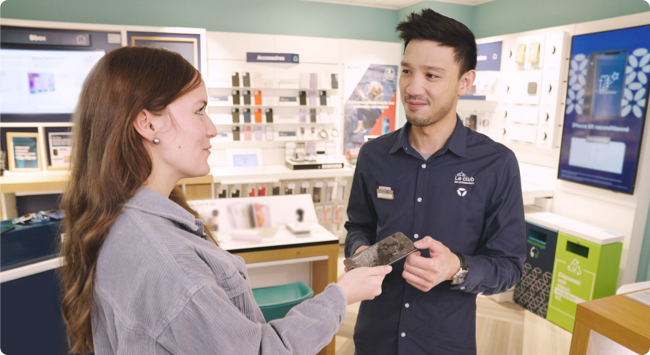 Conseiller de clientèle Bouygues Telecom avec une cliente, elle lui tend un téléphone cassé pour réparation