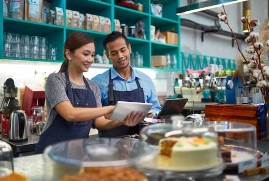 Deux restaurateurs souriants devant leur tablette tactile