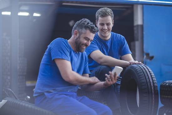 Deux professionnels souriants devant leur smartphone