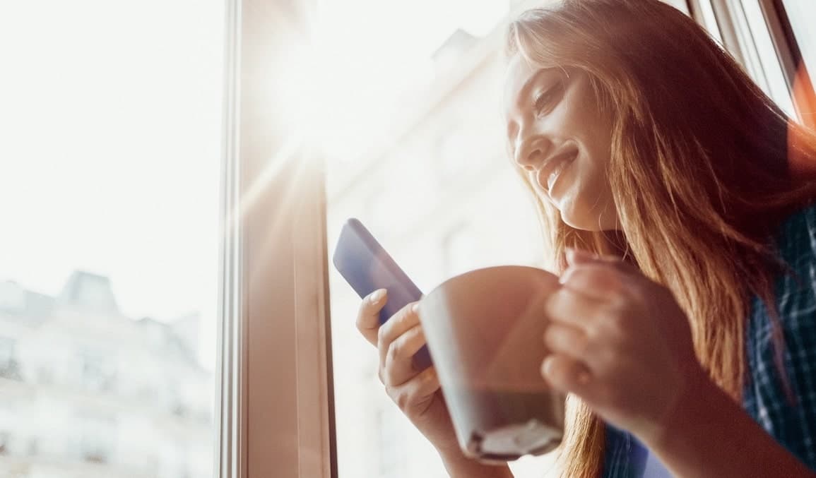 femme tasse smartphone fenetre soleil