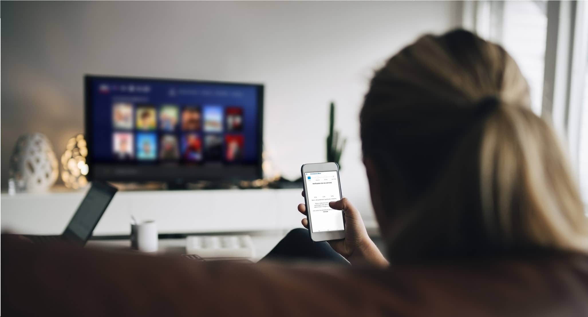 femme utilisant smartphone tv salon canape