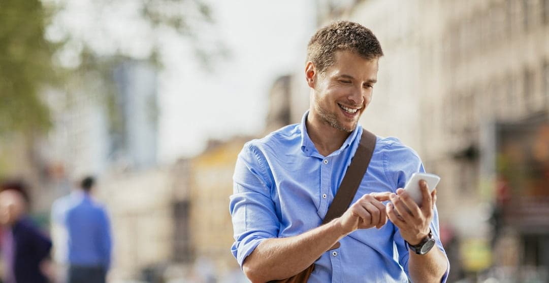 homme chemise utilisant smartphone rue