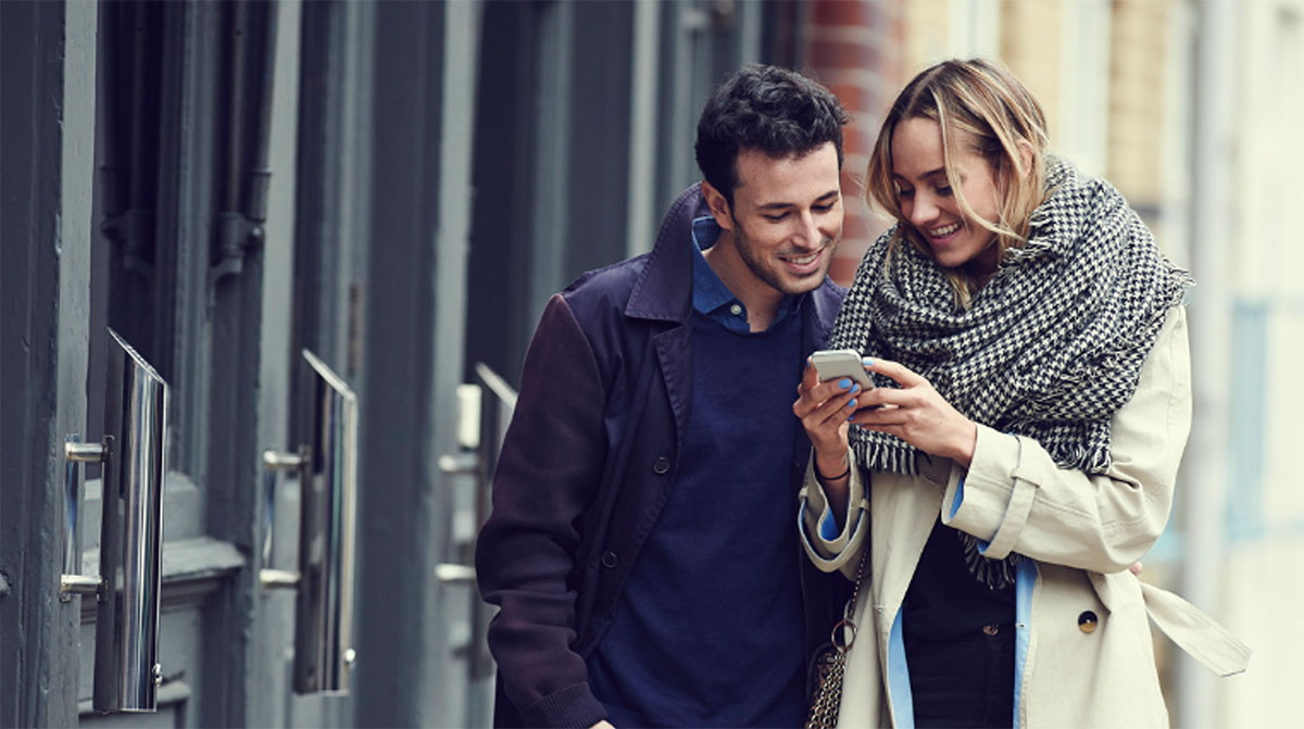image de couple homme femme utilisant smartphone dehors