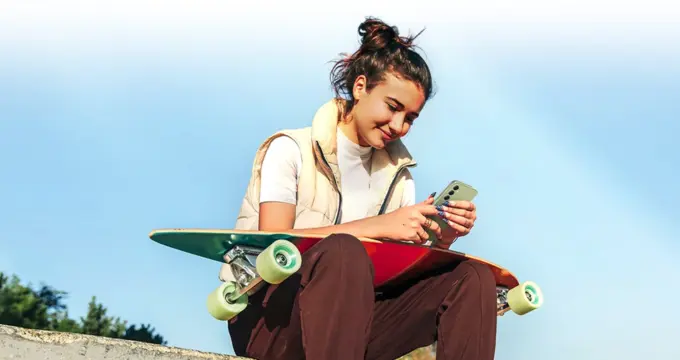Ado utilisant son smartphone pret de son skate-board