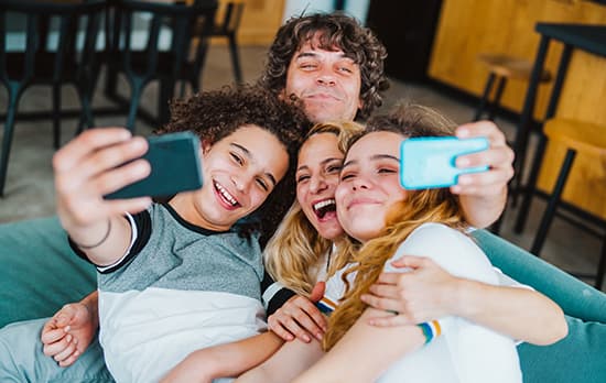 Famille heureuse prenant un selfie sur le canape du salon