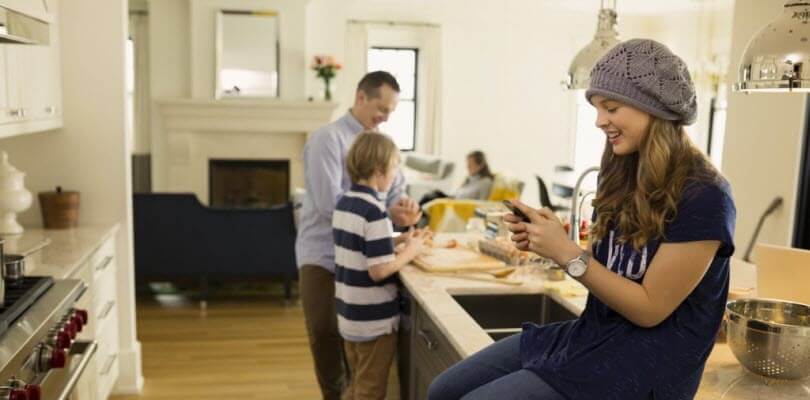 fille avec smartphone en famille à la maison