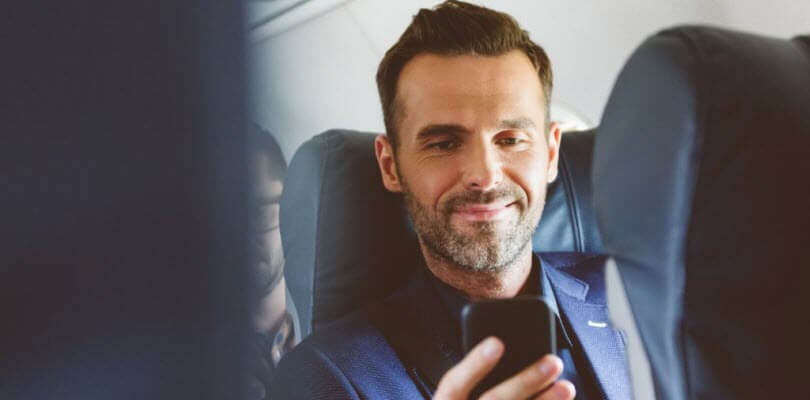 homme d'affaire sur smartphone dans avion