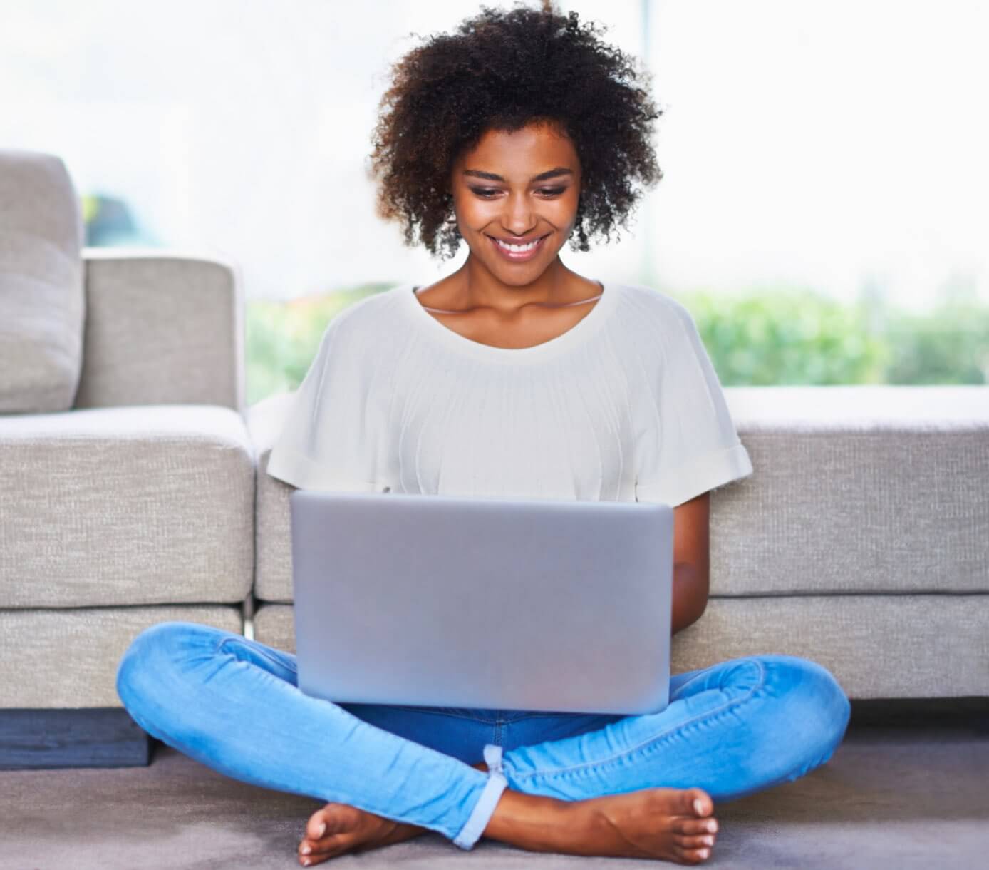 Jeune femme souriant devant son ordinateur à la maison