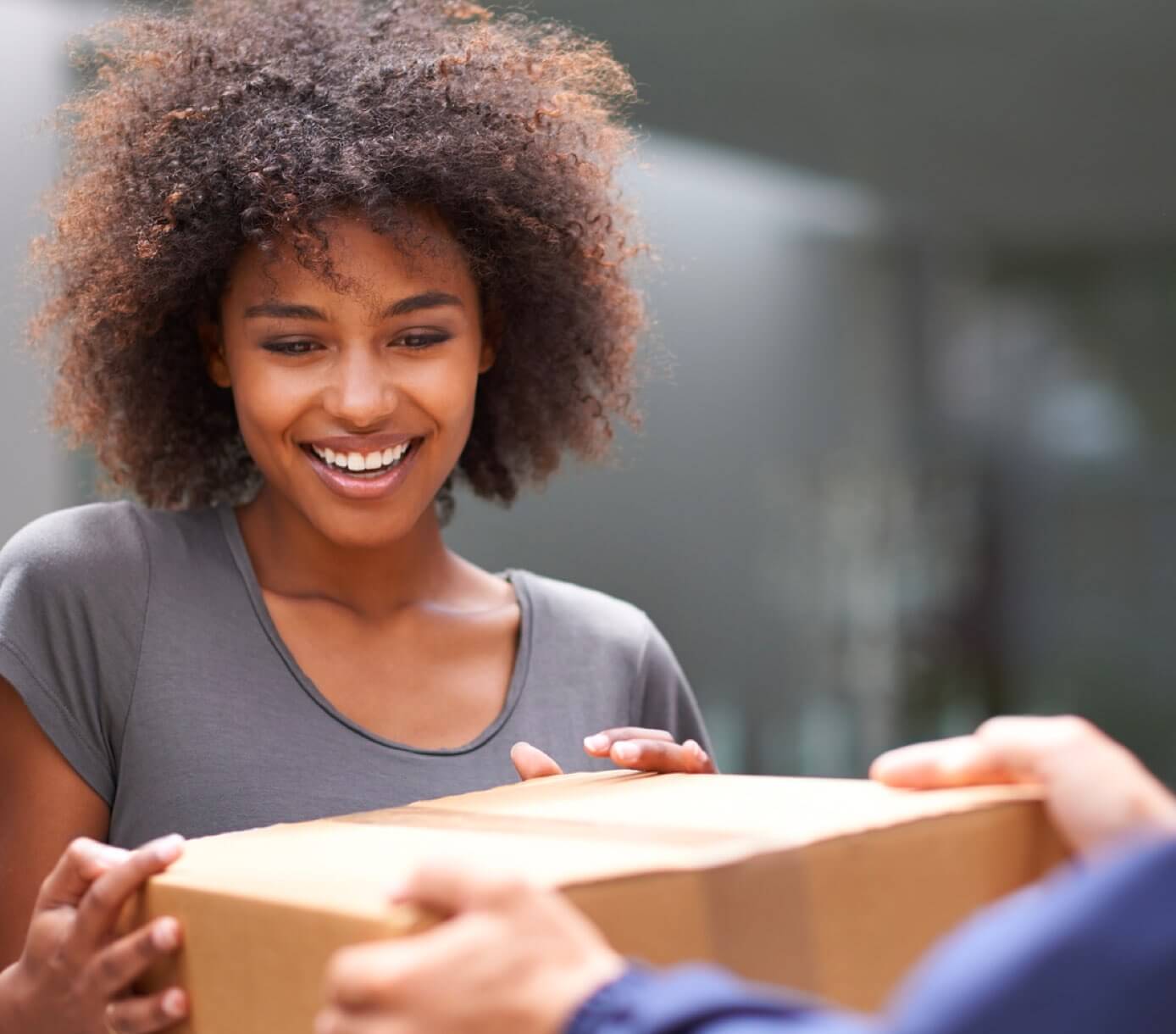 Jeune femme souriant à la réception de son colis