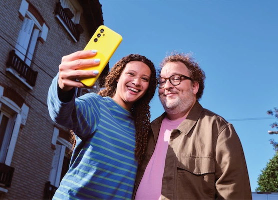Un homme et une femme sur un comptoir de cuisine, partageant un moment en consultant un téléphone.