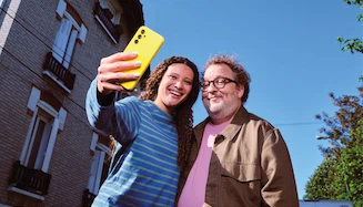 Un homme et une femme sur un comptoir de cuisine, partageant un moment en consultant un téléphone.